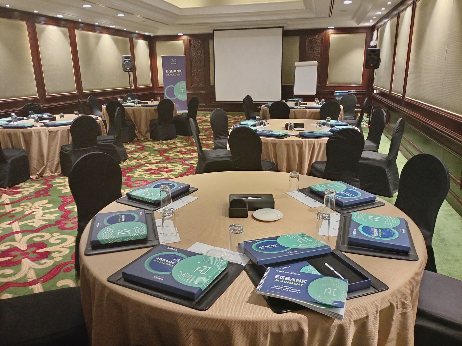 تجهيز قاعة فعالية EGBank AI Academy بالطاولات المستديرة والحقائب التدريبية